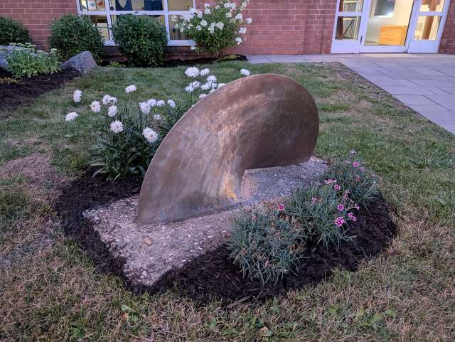 Plate-bande de marguerites et d'œillets autour d'une sculpture
