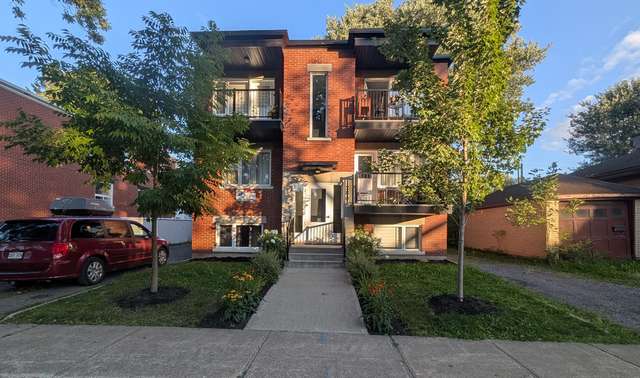 Façade d'un triplex en brique avec plate-bandes fleuries en soirée